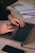 Hands typing on a laptop keyboard with a smartphone and notebooks on the desk.
