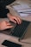 Hands typing on a laptop keyboard with mobile devices and notes nearby.