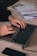 Close-up of hands typing on a laptop keyboard with paperwork on the desk.