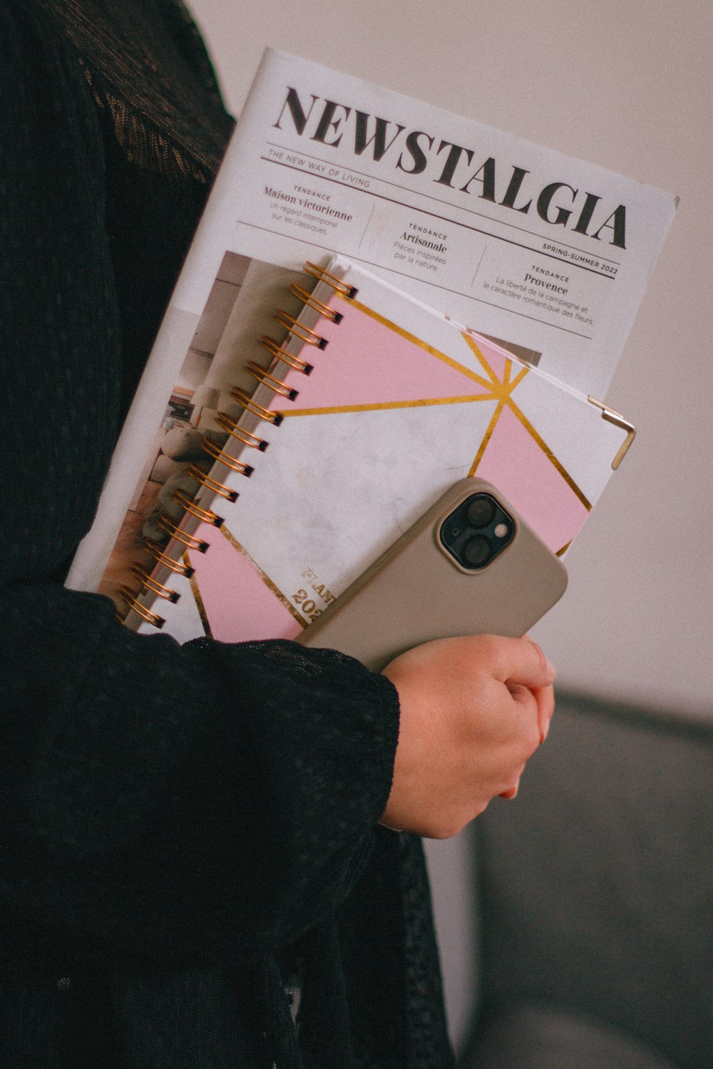 a person holding a magazine and a cell phone