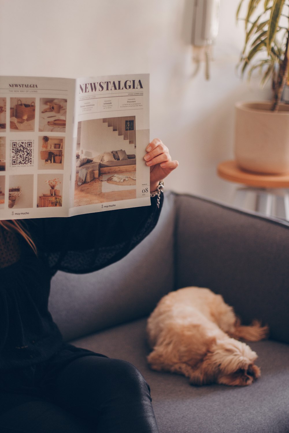 a woman sitting on a couch reading a newspaper