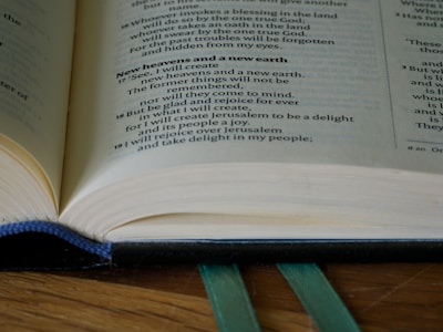 Close-up of an open vintage book with a golden bookmark resting on a dark green velvet surface.