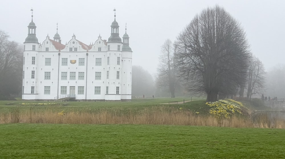 a large white building sitting on top of a lush green field