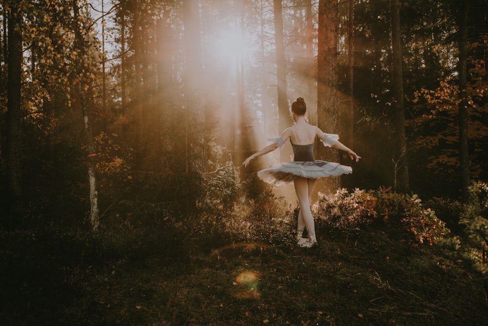 Una donna in abito bianco sta ballando nel bosco