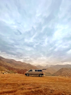 a van is parked in a field with mountains in the background