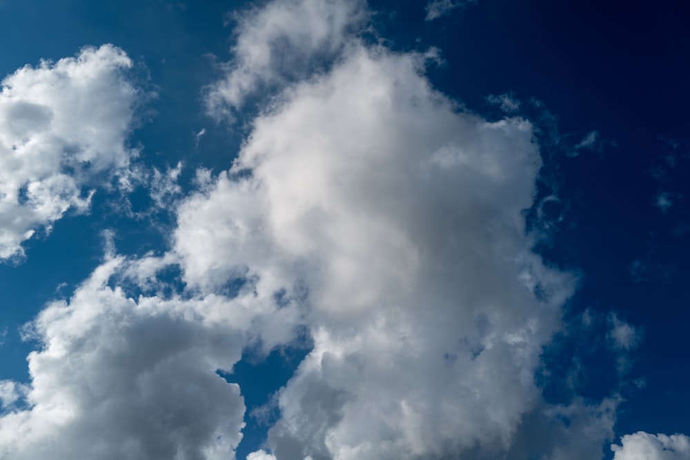 a plane flying through a blue cloudy sky