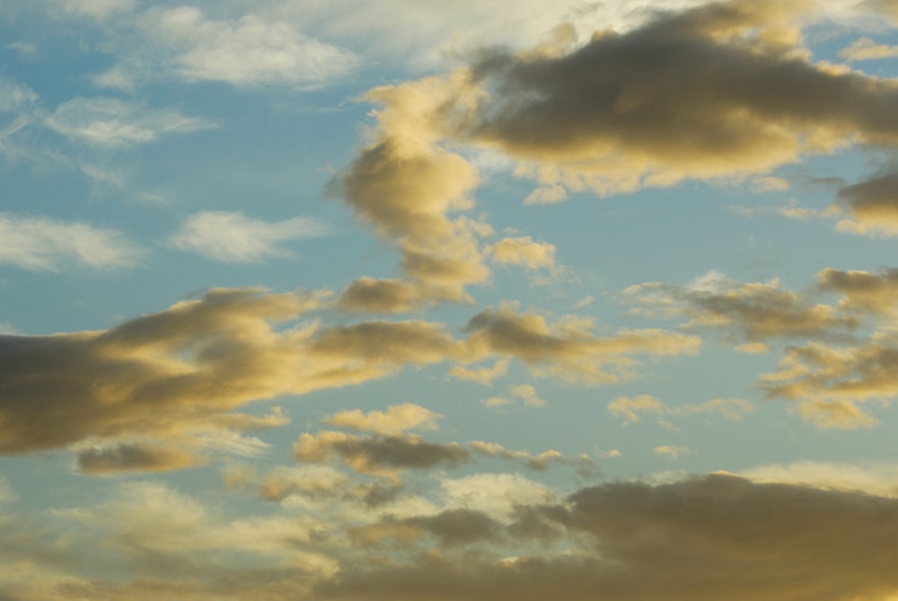 a plane flying through a cloudy blue sky