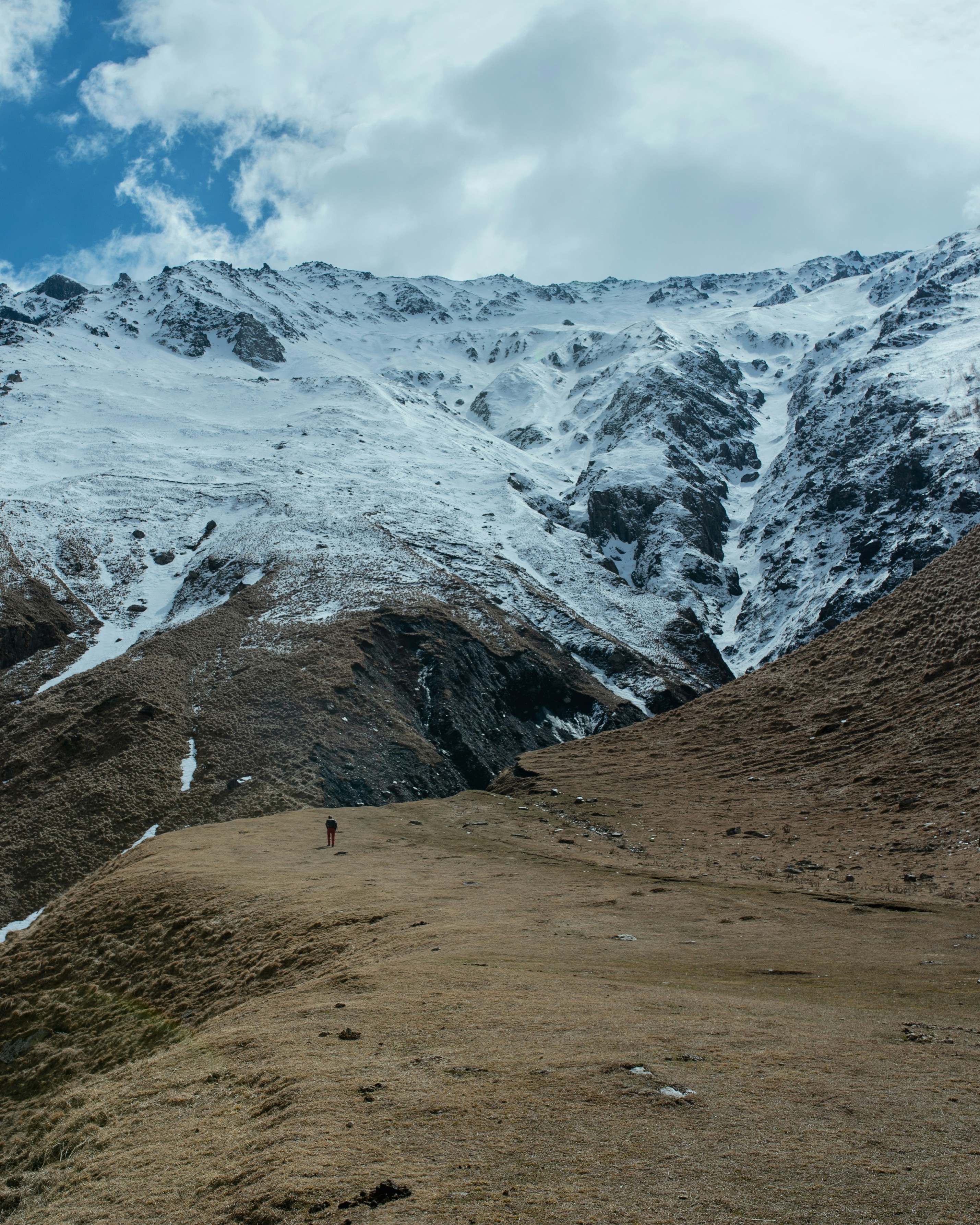 a person walking up a hill with a snow covered mountain in the background