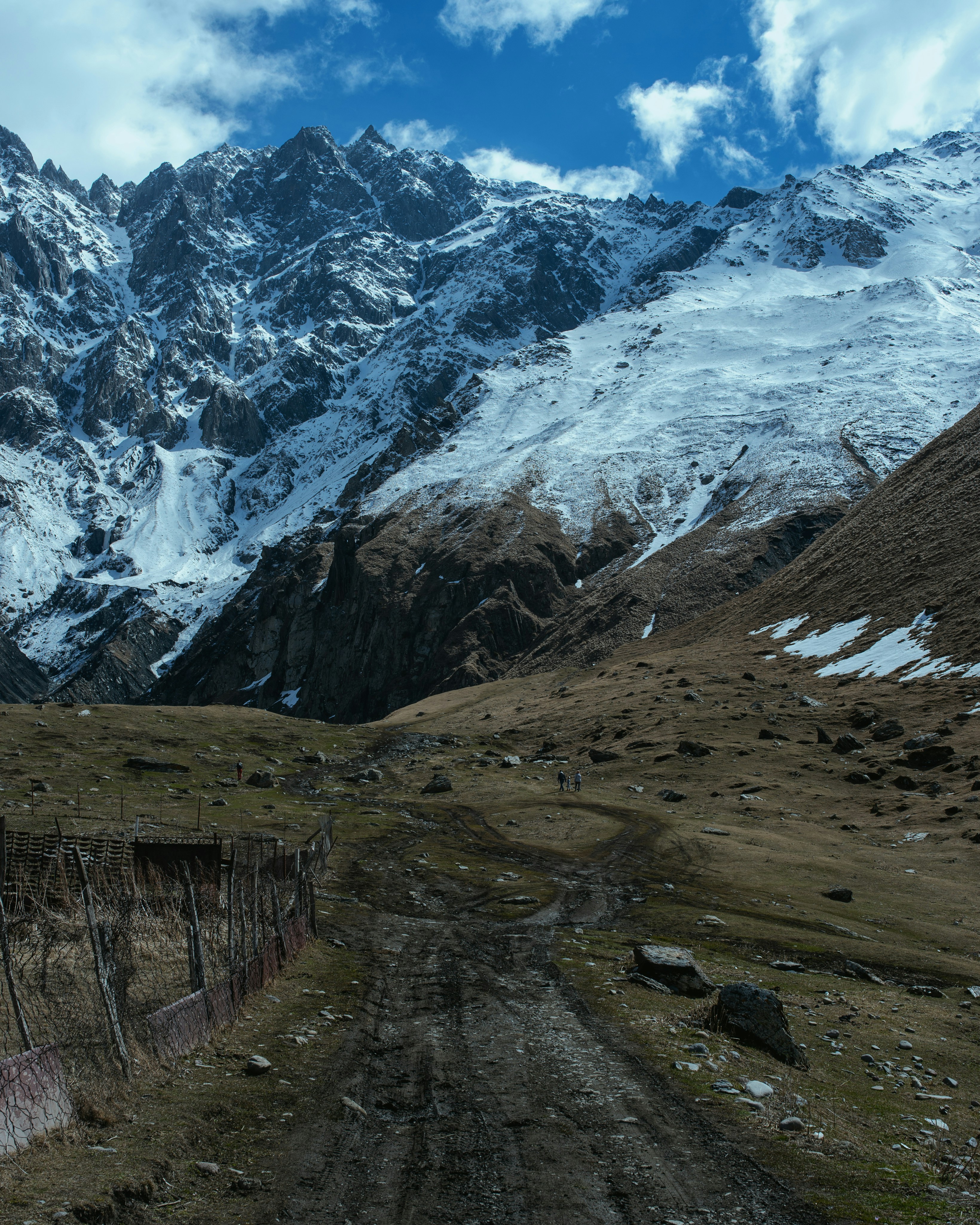 a dirt road in front of a snow covered mountain