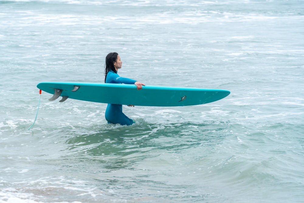 a woman holding a surfboard in the ocean