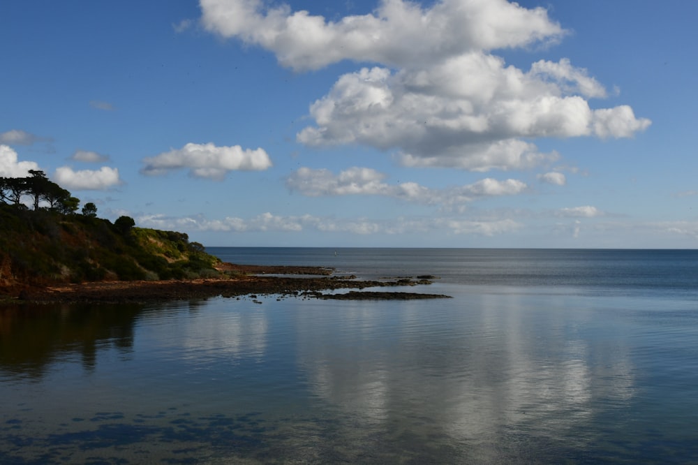 a body of water surrounded by a lush green hillside