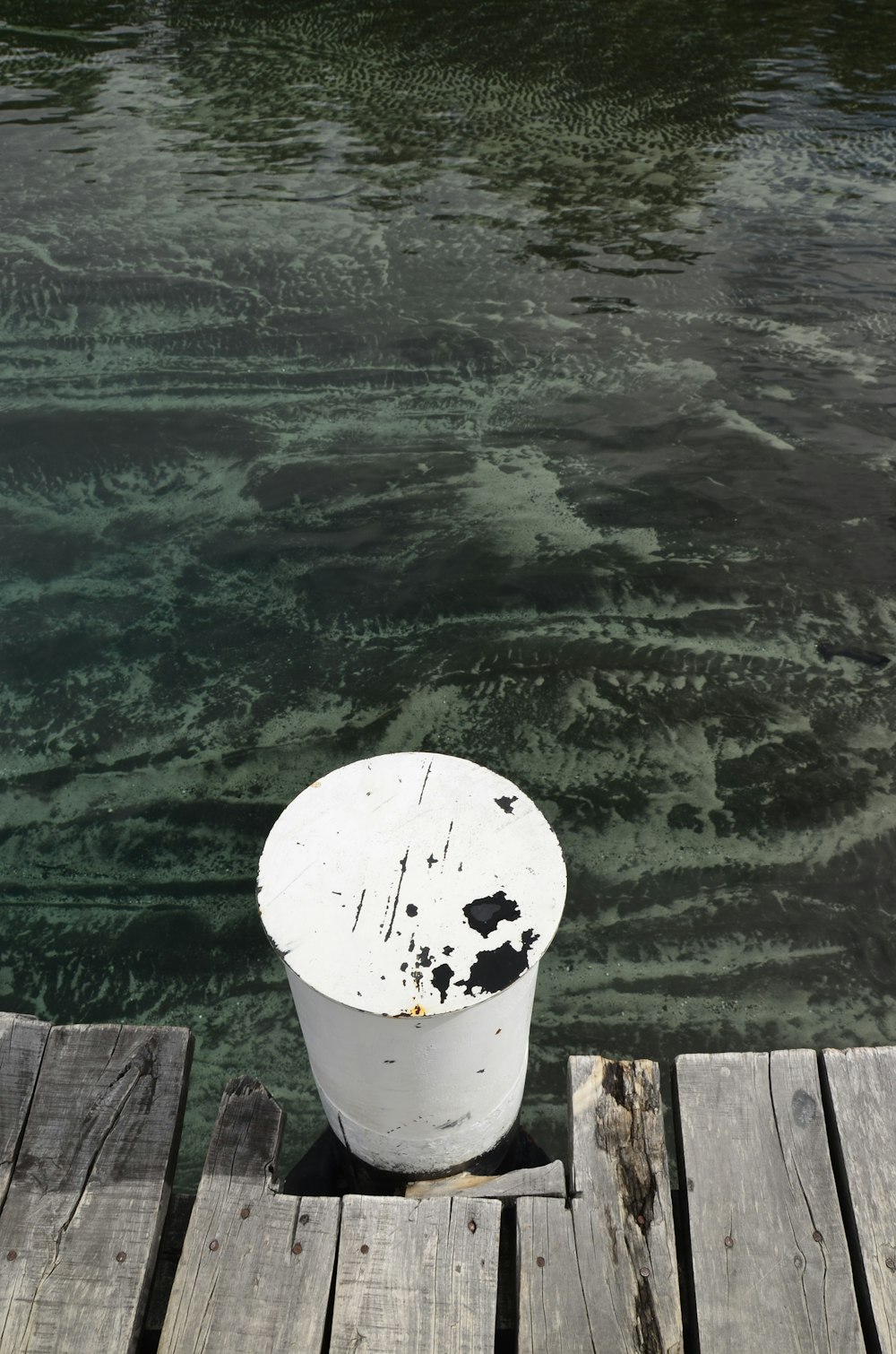 a white bucket sitting on top of a wooden dock