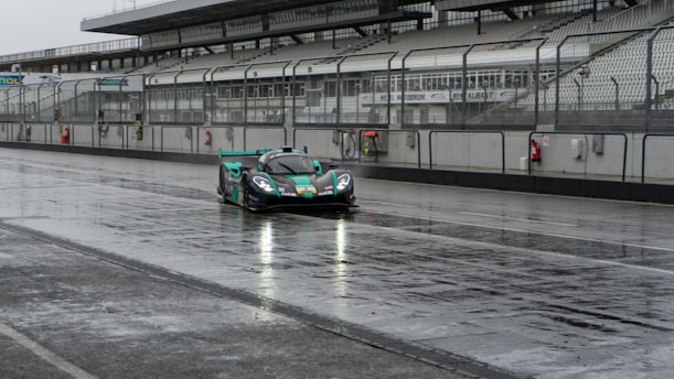 A sleek Formula 1 car speeding through a rain-soaked track under dramatic stormy skies.