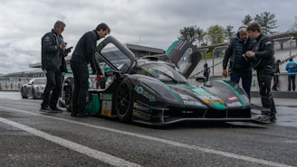 A dynamic shot of team members tuning a race car under bright sunlight at the Zagreb track.