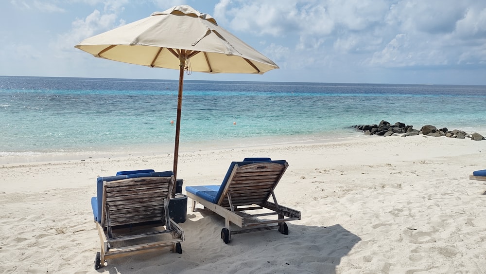 two lounge chairs and an umbrella on a beach