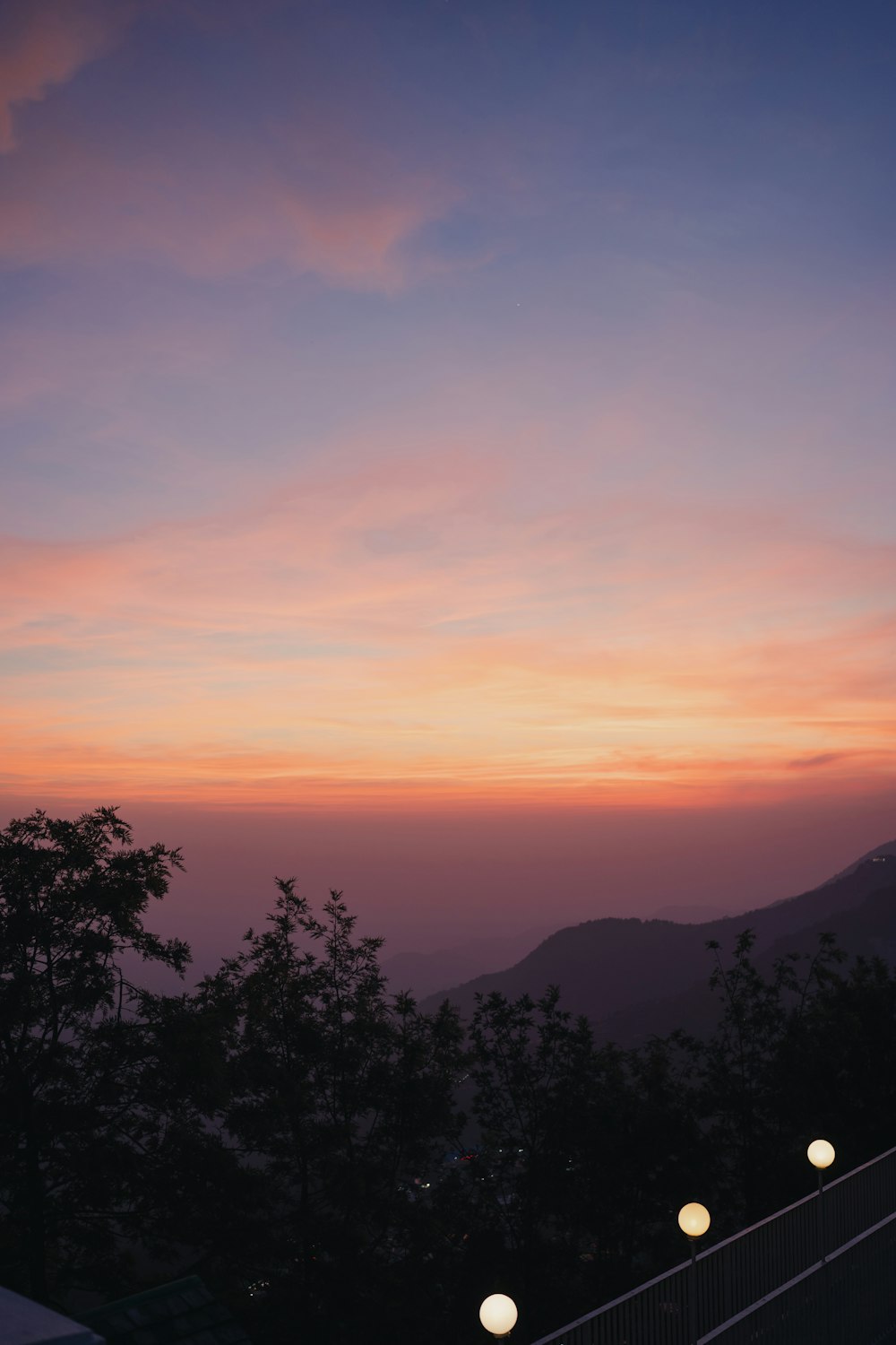 the sun is setting over the mountains and trees