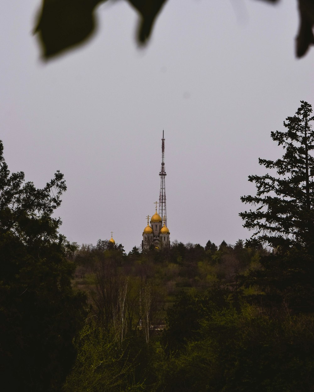 a radio tower on a hill with trees in the foreground