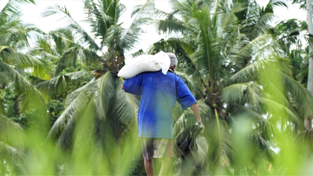 a man carrying a bag on his back through a jungle