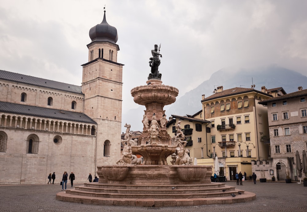 a fountain in front of a building with a clock tower in the background