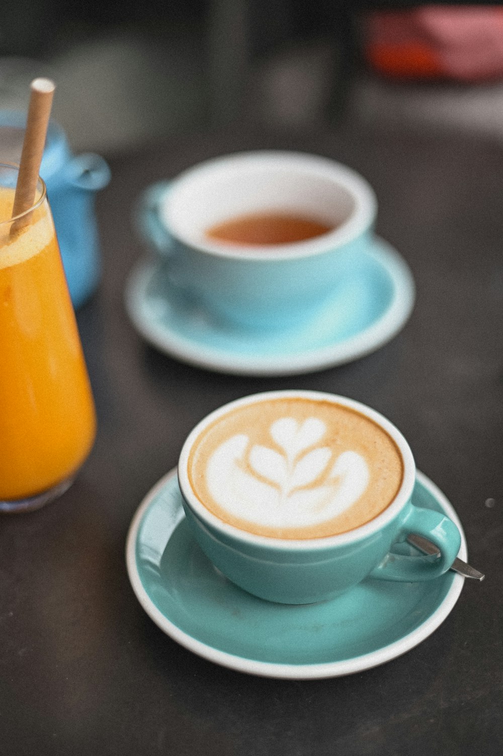 a cappuccino on a saucer and a cup of orange juice