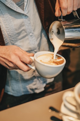a person pouring a cup of coffee into a cup