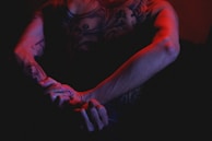 A black and red intricate sleeve tattoo wrapping an arm, photographed under moody light.