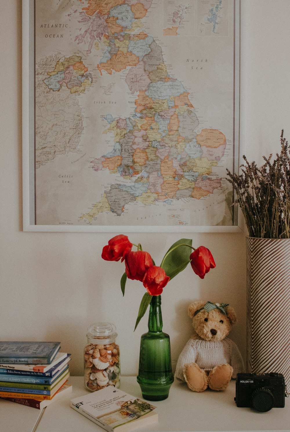 a teddy bear sitting next to a vase of flowers