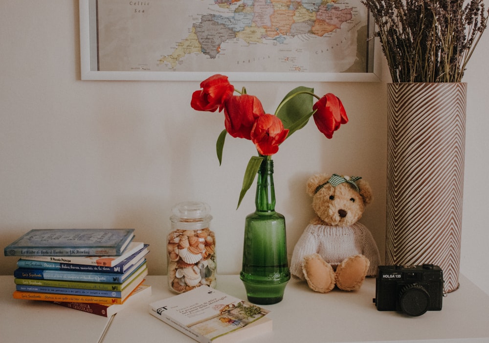 a teddy bear sitting next to a vase with flowers