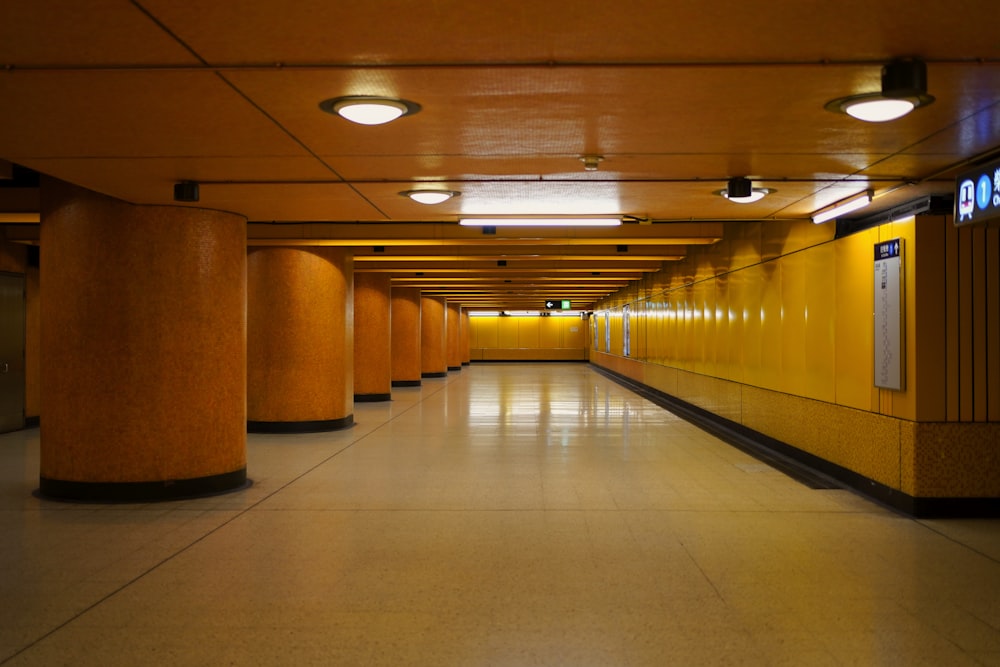 a long hallway with yellow urinals and lights