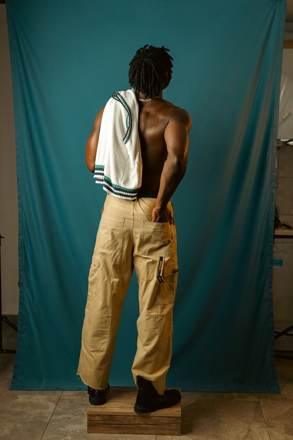 a man with dreadlocks standing in front of a blue backdrop