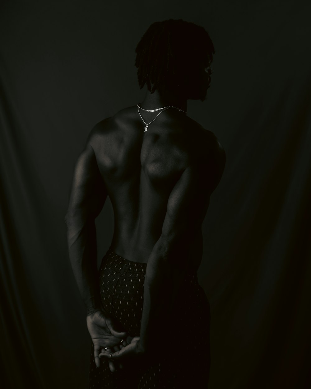 a man with no shirt standing in a dark room