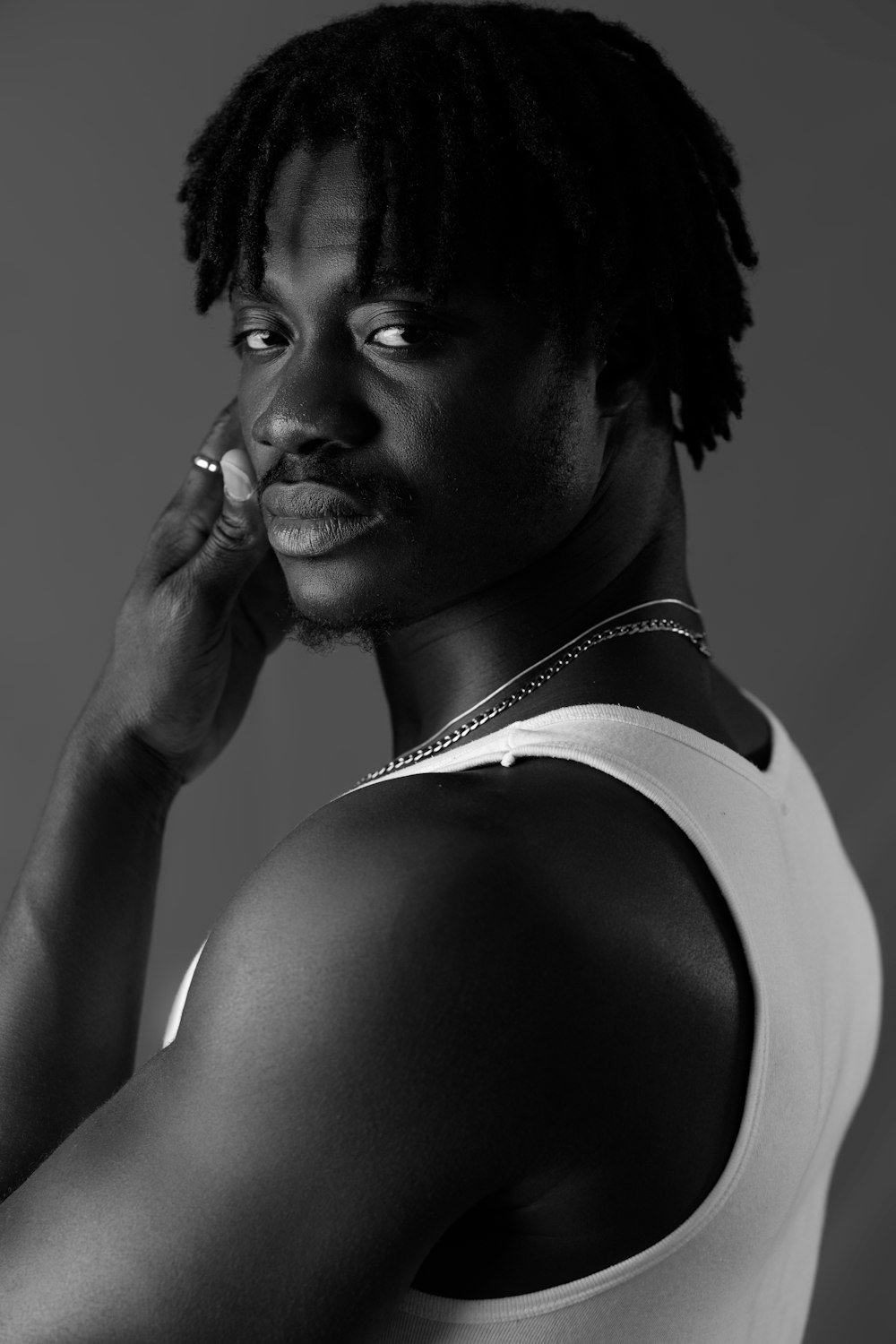 a man with dreadlocks and a white tank top