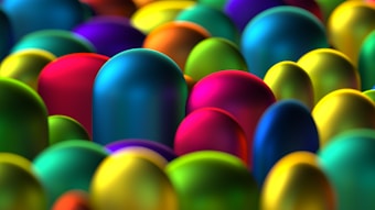 A vibrant collection of smooth, rounded capsules in various vivid colors, such as blue, red, yellow, and green, creates a lively and energetic visual pattern with a glossy surface texture.