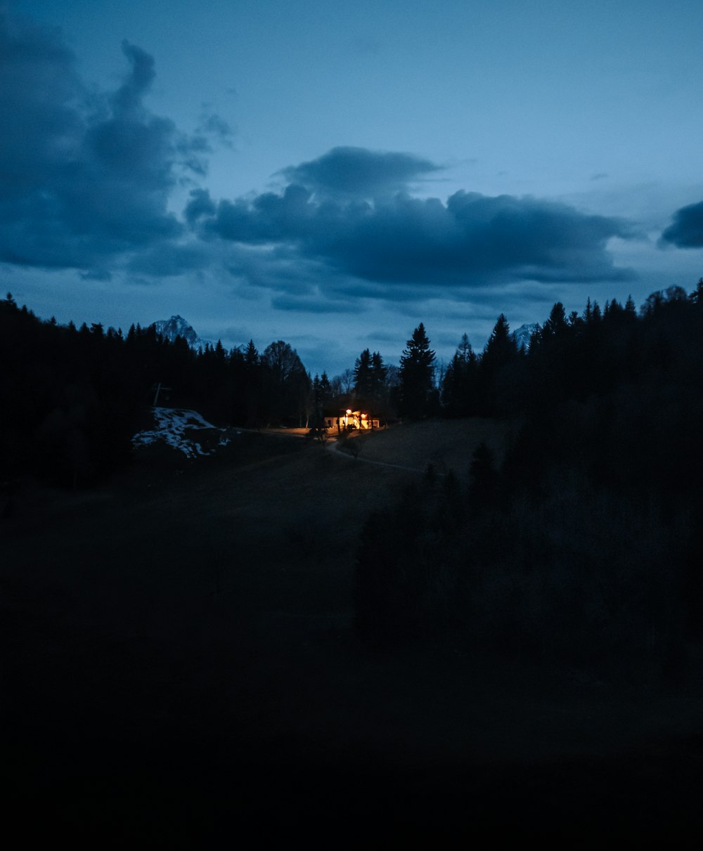 a cabin is lit up at night in the woods