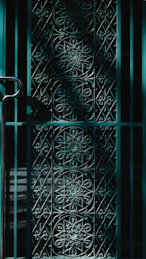 Finished steel gate with intricate ironwork design, gleaming under sunlight.