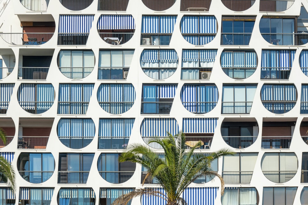 a tall building with many windows and palm trees in front of it