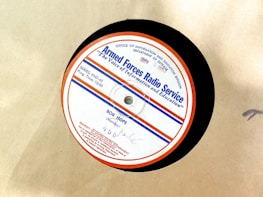 A vintage vinyl record from the Armed Forces Radio Service, featuring a label with text and logos. The label is circular with a red outer rim, a blue line, and several inscriptions including the name 'Bob Hope' and program details. The background is a plain beige surface.