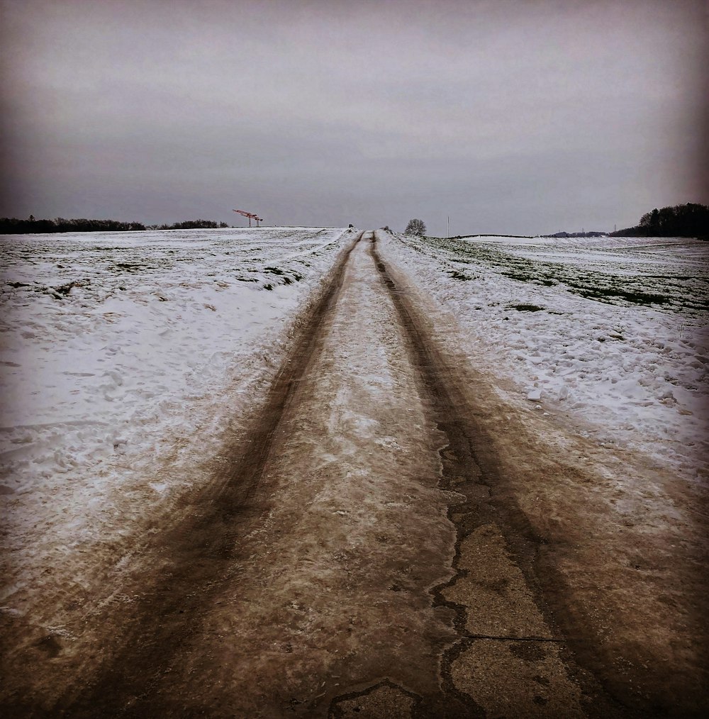 a snow covered field with a road in the middle of it