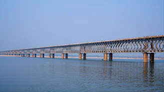 A sturdy steel bridge spanning a wide river under clear blue skies.
