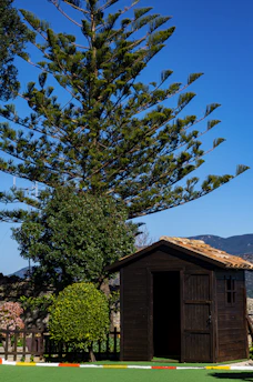 A charming wooden wendy house with a pitched roof set in a sunny North West garden.