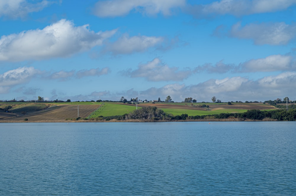 a large body of water surrounded by a lush green field