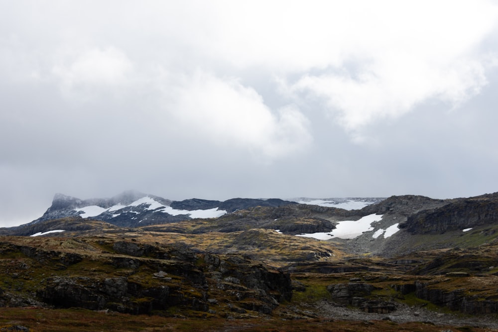 a mountain covered in snow and grass under a cloudy sky