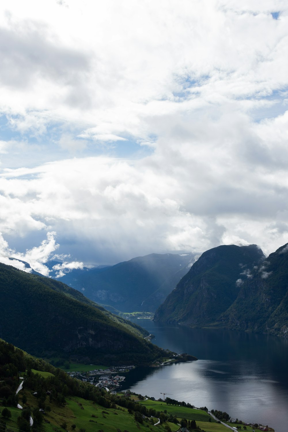 a lake surrounded by mountains under a cloudy sky