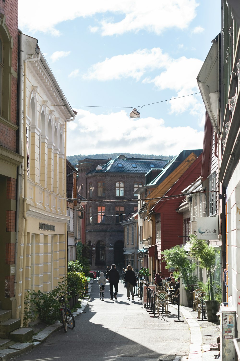 a narrow city street with people walking down it