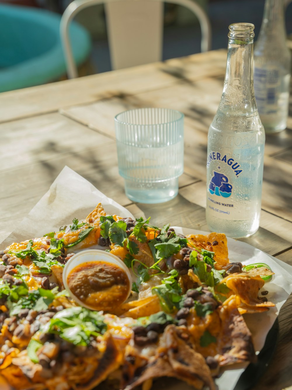 a plate of nachos and a bottle of water on a table