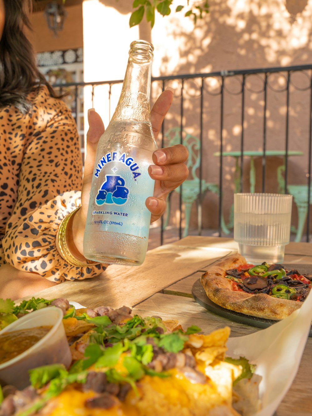 a woman holding a bottle of water over a plate of food