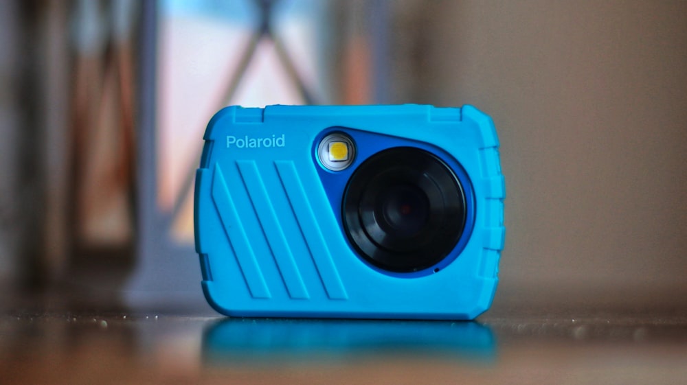 a blue camera sitting on top of a wooden table