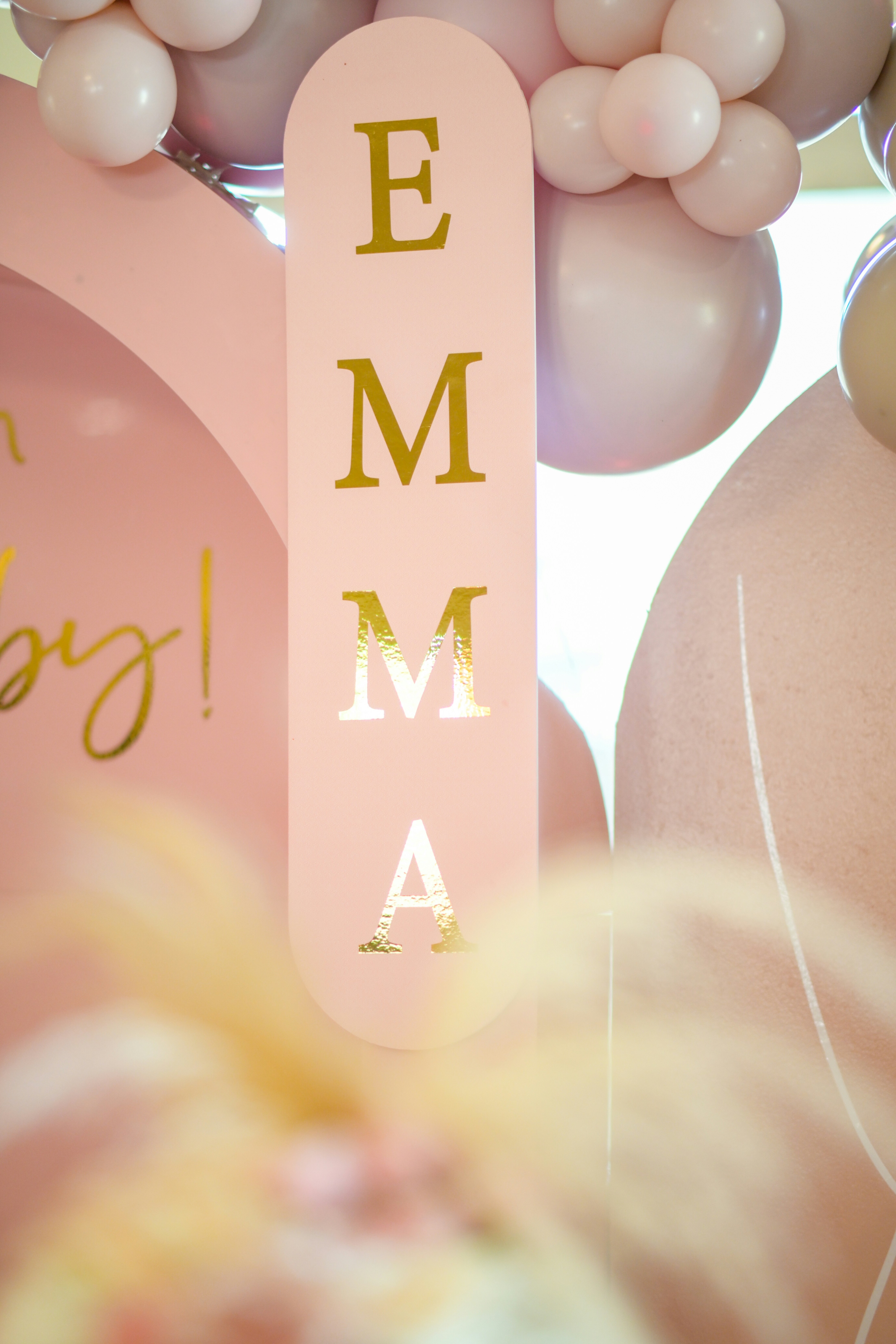 a pink sign with gold lettering and balloons