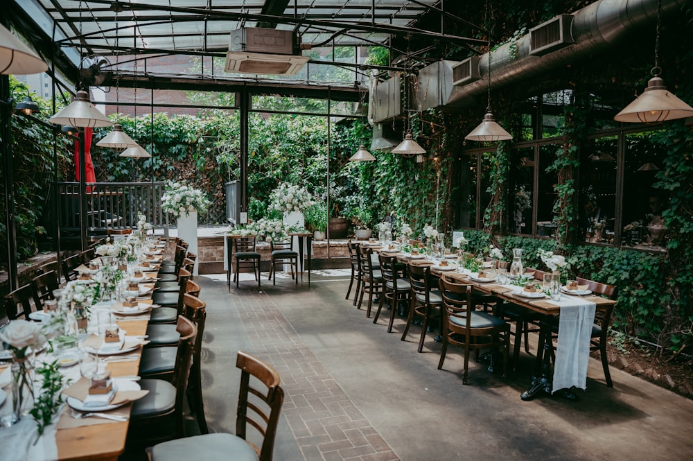 a long table set for a formal dinner in a greenhouse