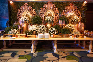 A lavish buffet setup with golden accents and rich maroon drapes under soft ambient lighting.